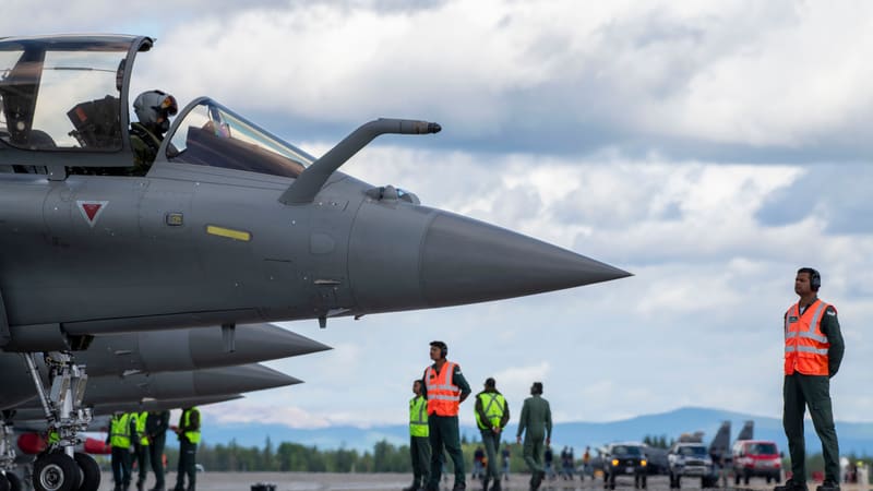 Indian Air Force Rafale fighters lined up on a runway with ground crew in orange vests