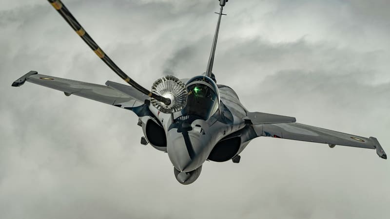 A Qatar Emiri Air Force Rafale, seen from the front and above, refuelling from a tanker's hose and drogue among clouds