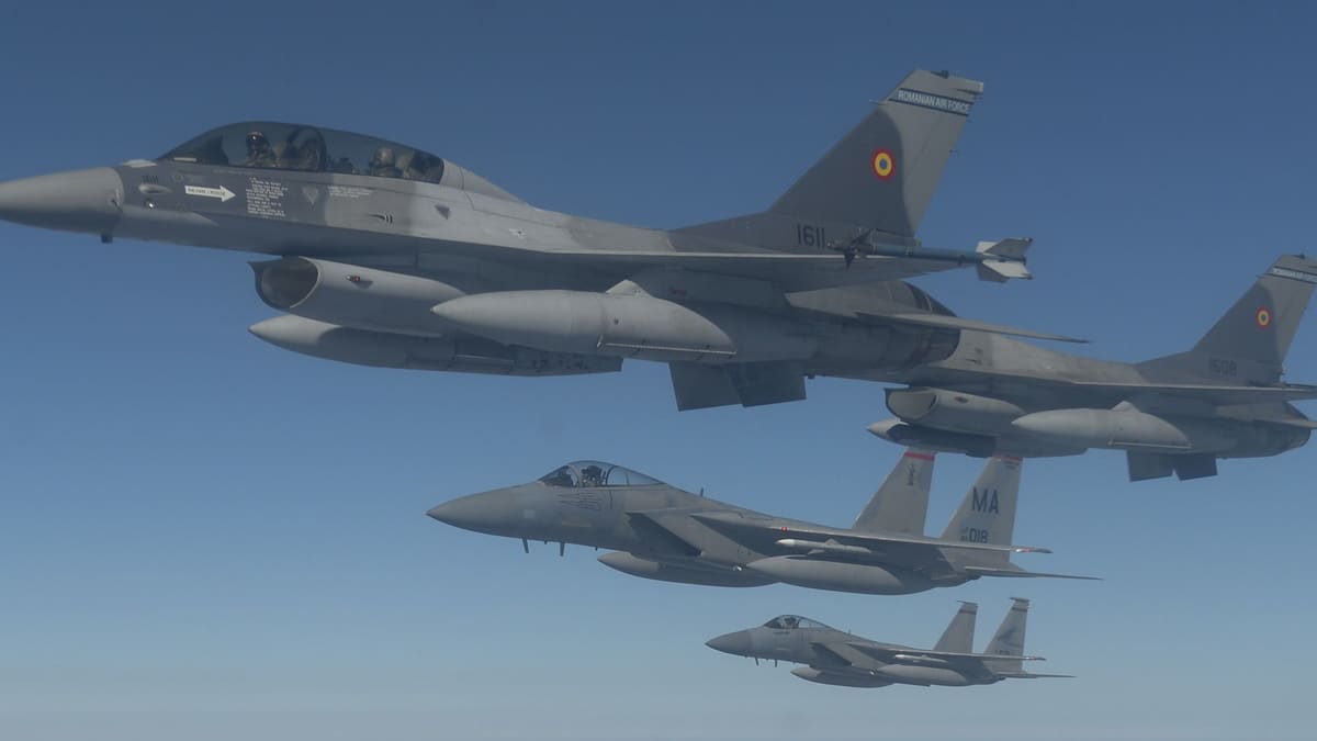 Two Romanian Air Force F-16s flying in formation with two U.S. F-15C Eagles above a hazy landscape