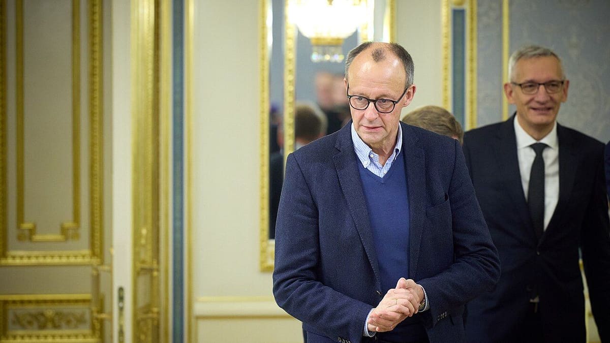 Friedrich Merz in a navy jacket and glasses walks into a gilded room, file photo from December 2024.