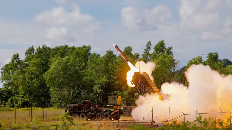 US Army Patriot launcher firing a PAC-2 interceptor missile in a burst of smoke beside a tree line