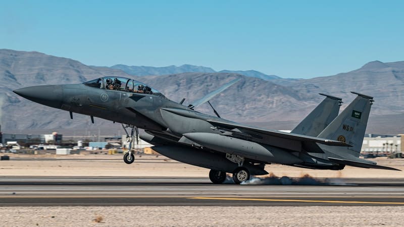 Royal Saudi Air Force F-15SA fighter jet touching down on a desert runway, with mountains behind