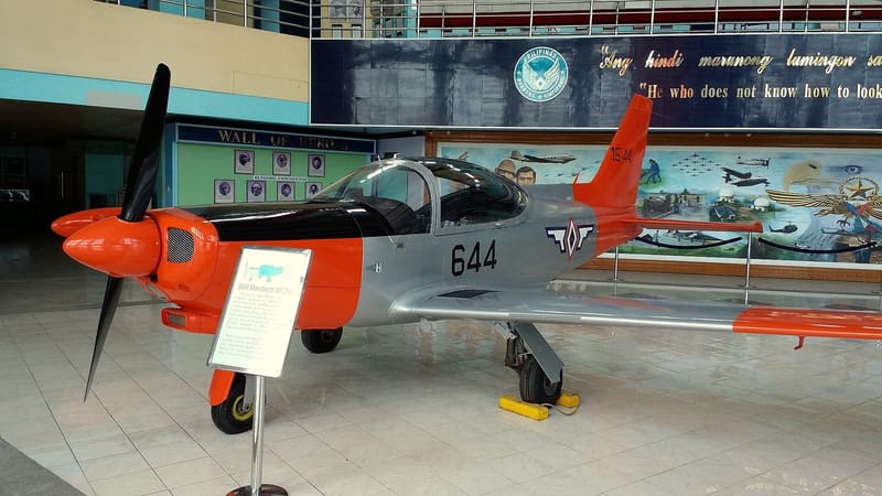 Orange and silver SF-260 trainer aircraft on display inside a museum hall