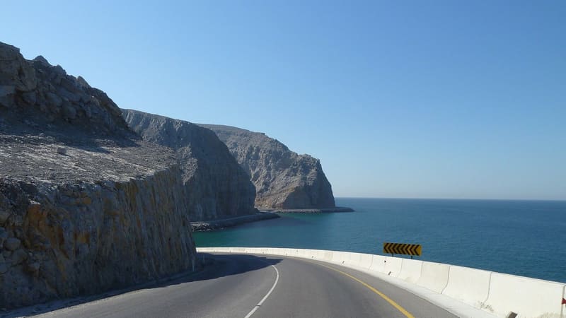 Coastal road cut into rocky cliffs above the sea near Khasab on Oman's Musandam Peninsula