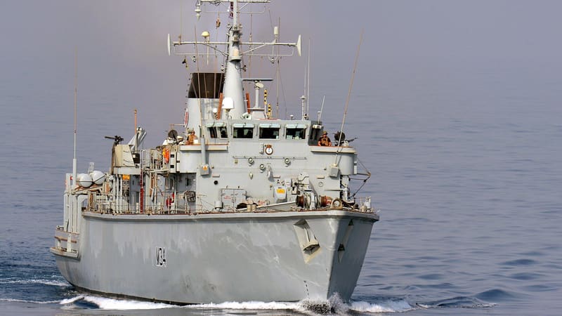 Royal Navy minehunter HMS Middleton, pennant M34, under way in hazy Gulf waters with gunners on the bridge wings