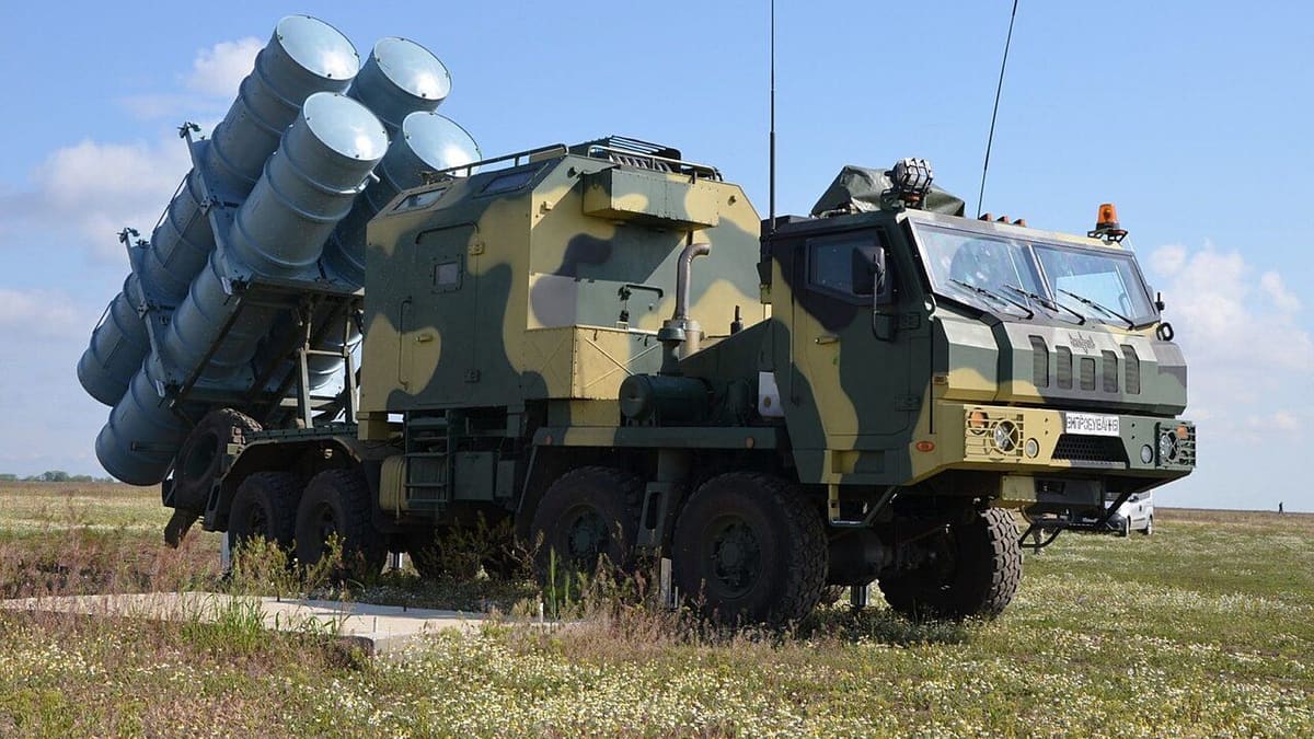 A camouflaged Ukrainian truck carrying four tilted Neptune missile canisters stands on a grassy field