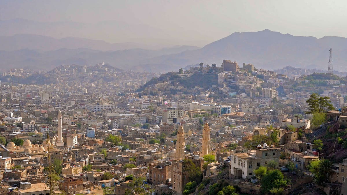 Hazy view across the hillside city of Taiz, Yemen, with old minarets in front and mountains behind