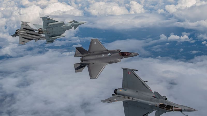 An RAF Typhoon and French Rafale peel away at upper left as a U.S. F-35A and a second Rafale bank over a sea of cloud