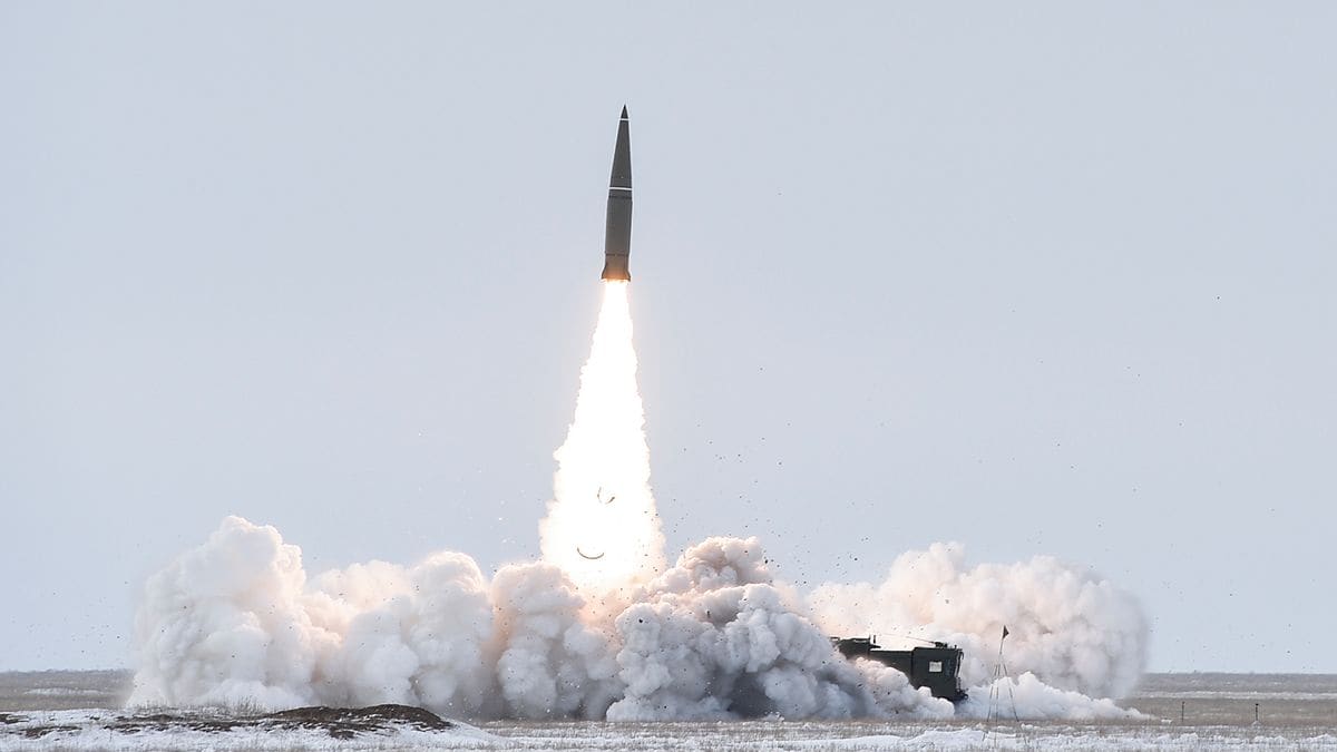 An Iskander-M ballistic missile climbs above a cloud of exhaust from its launcher on a snow-covered firing range.