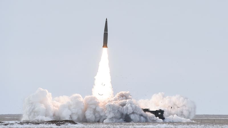 An Iskander-M ballistic missile climbs above a cloud of exhaust from its launcher on a snow-covered firing range.