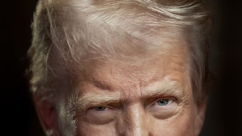 Close-up official portrait of President Donald Trump in a blue suit with a flag lapel pin