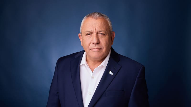 Portrait of Israeli opposition leader Gadi Eisenkot in a navy jacket against a blue background
