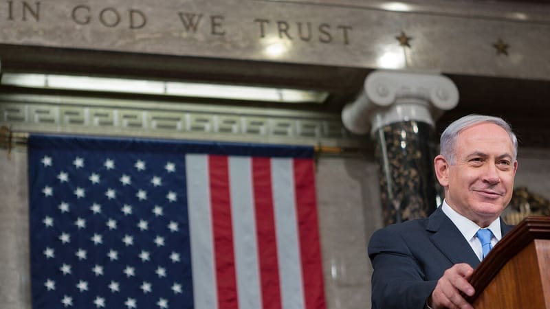 Benjamin Netanyahu smiling at a lectern in front of a US flag, in a 2015 file photograph