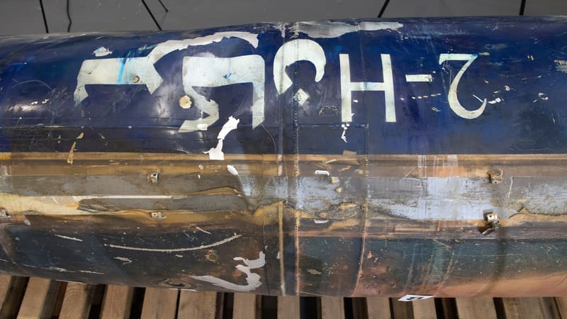 Dark blue missile body with painted white markings resting on wooden pallets