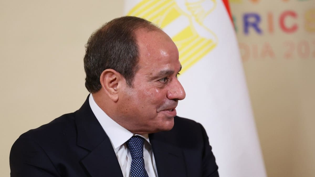 Egyptian President Abdel Fattah el-Sisi in profile in a dark suit, in front of an Egyptian flag and a BRICS India backdrop