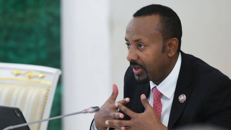 Abiy Ahmed gesturing with both hands as he speaks into a microphone at a conference table