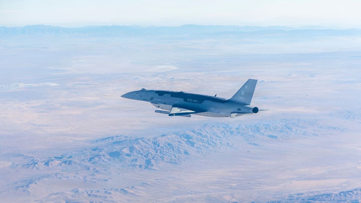 A grey YFQ-44A Fury drone with U.S. Air Force markings flies above the brown Mojave Desert and distant mountains
