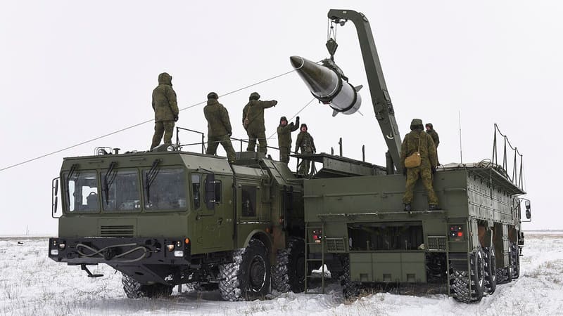 Russian soldiers use a crane to load a missile onto an Iskander-M launcher truck on a snowy test range